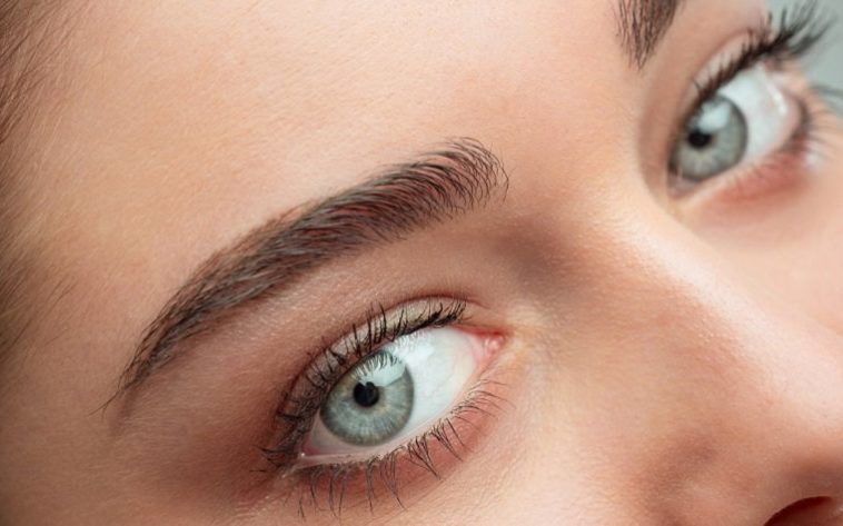 Naheaufnahme eines Gesichts mit betonten Augenbrauen und strahlend blauen Augen.