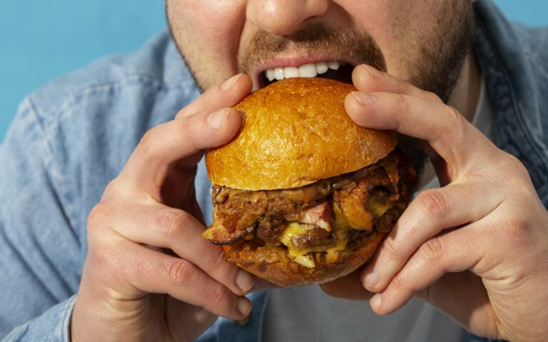 Eine Person hält einen saftigen Burger mit einem goldenen Brötchen und beabsichtigt, ihn zu essen.