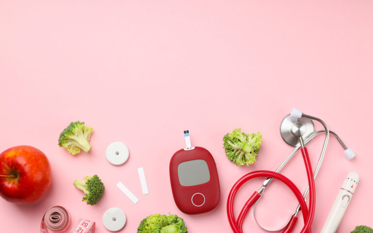 Gesunde Lebensmittel und medizinische Geräte auf rosa Hintergrund, darunter Apfel, Brokkoli, Blutzuckermessgerät und Stethoskop.