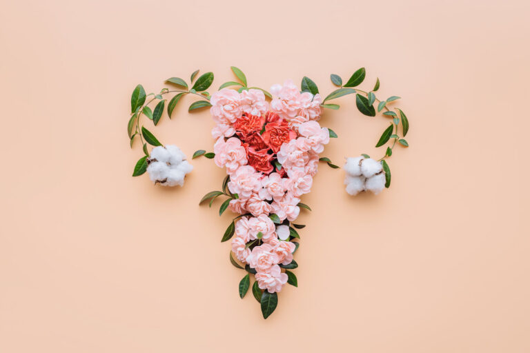 vaginaleGesundheit.jpeg Ein florales Arrangement in Herzform aus rosa Blumen und Baumwollblüten auf einem pfirsichfarbenen Hintergrund.