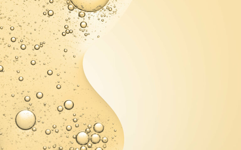Goldfarbener Flüssigkeitshintergrund mit zahlreichen Blasen, die eine glatte, fließende Struktur bilden.